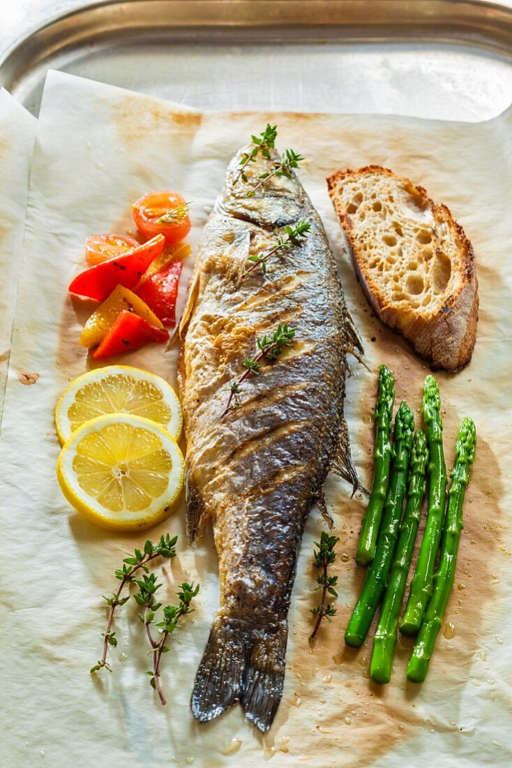 Seabass with asparagus, lemons and bread on baking paper