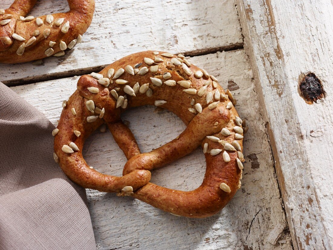 A sunflower seed pretzel on white floor boards