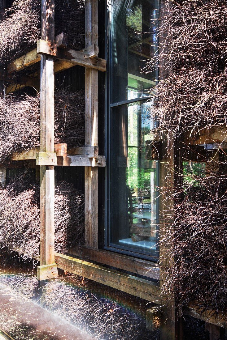 Holzgerüst mit Reisigbündeln an Wohnhausfassade mit Ausschnitt für Fenster