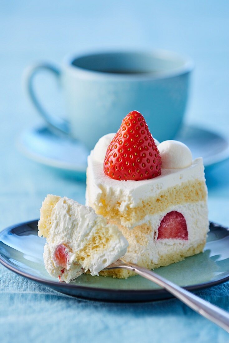 Ein Stück Sahnetorte mit Erdbeeren, angebissen