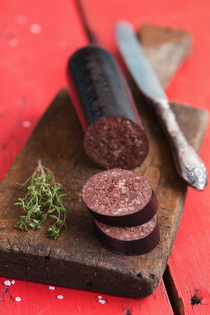 Black pudding, sliced, and fresh thyme on a chopping board