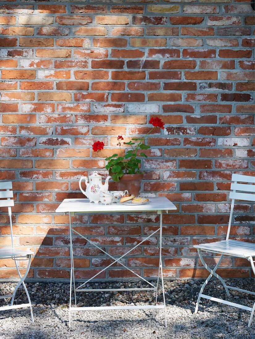 White garden table and chairs against brick façade