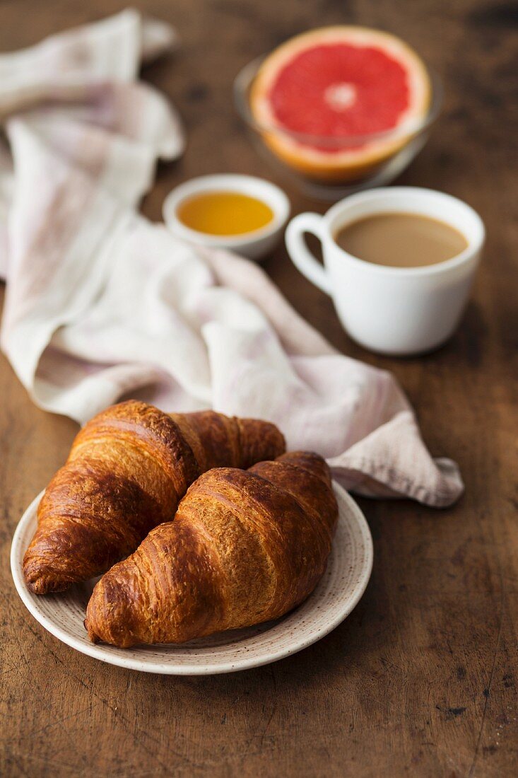 Croissants with coffee, honey and grapefruit for breakfast