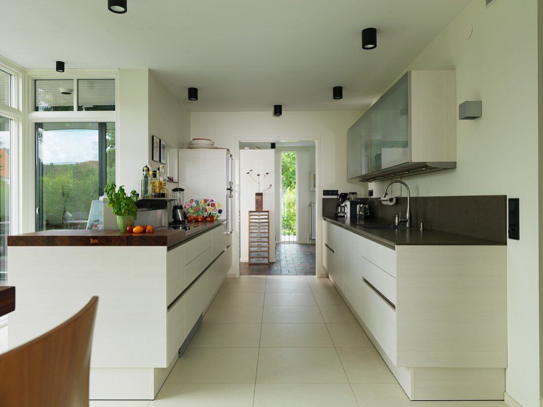 Two facing counters in open-plan kitchen with large floor tiles and doorway leading to foyer in background
