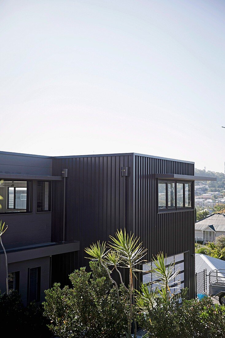 Antrazithfarbene Metallfassade eines modernen, kubischen Wonhauses mit Blick über Brisbane