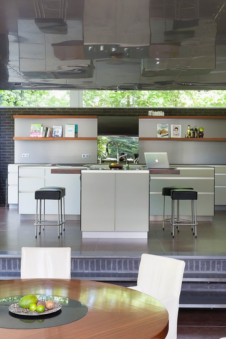 Elegant fitted kitchen on raised platform with ribbon window and reflective metal ceiling