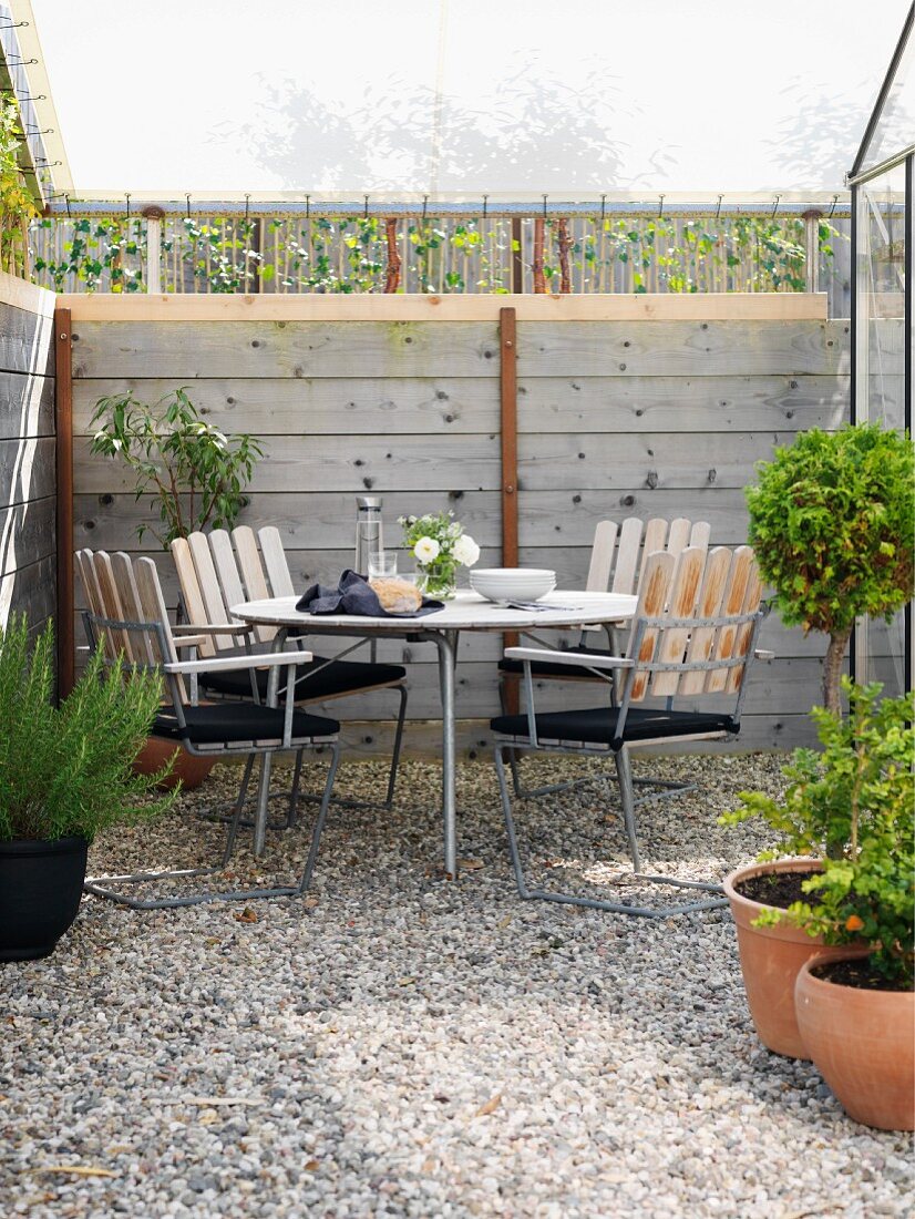 Seating area on small gravel terrace below awning with wooden frame