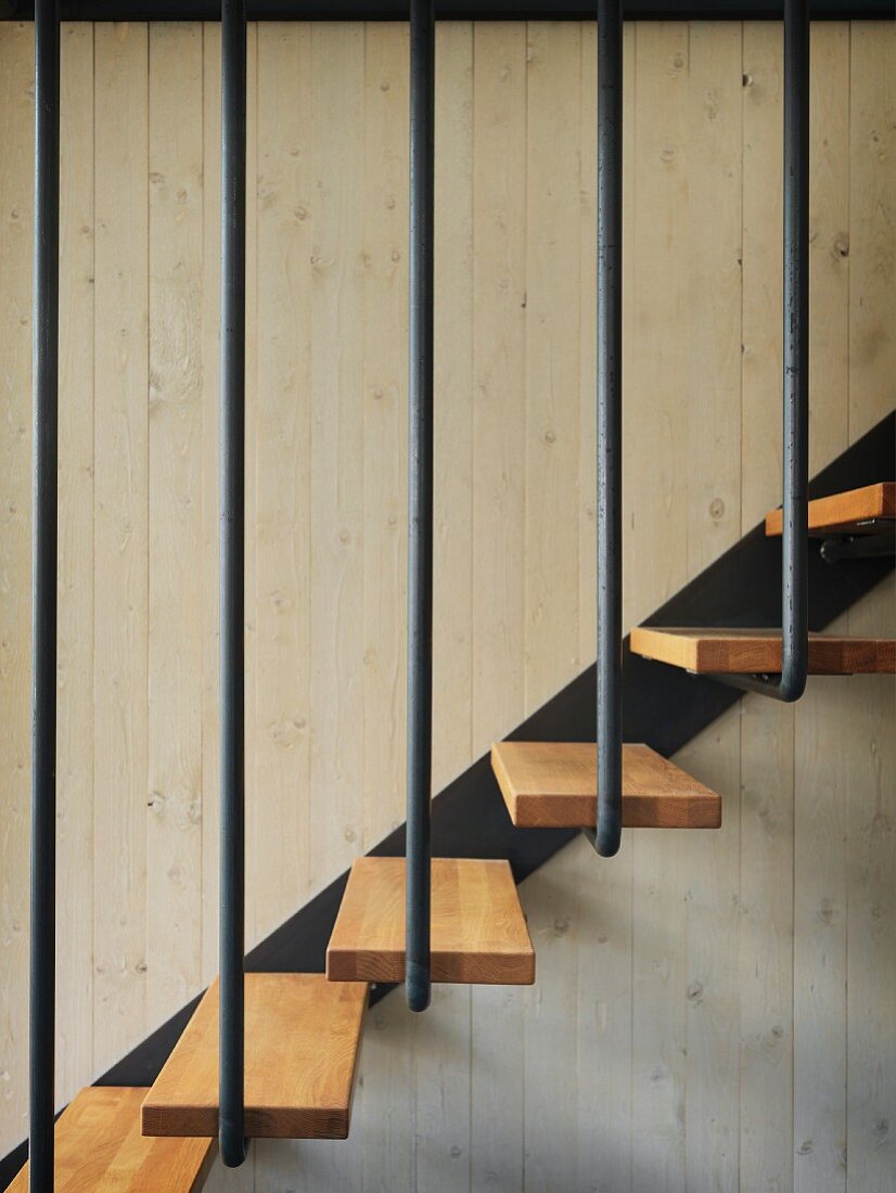 Ausschnitt einer Treppe mit Holztrittstufen und schwarzem Metallgeländer