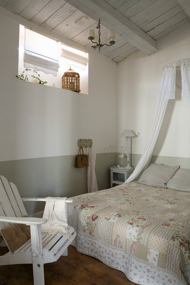 Nostalgische Tagesdecke auf Doppelbett, oberhalb kleiner Stoffhimmel in schlichtem Schlafzimmer