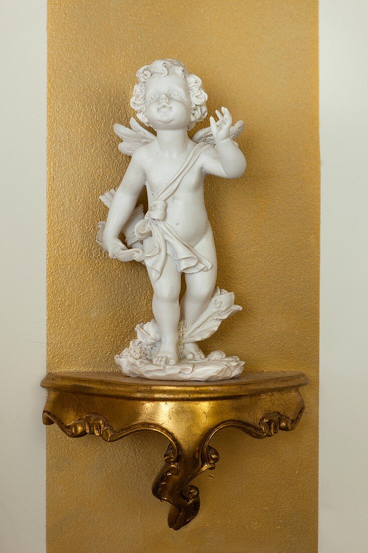 Cherub on gilt bracket on gold stripe on wall