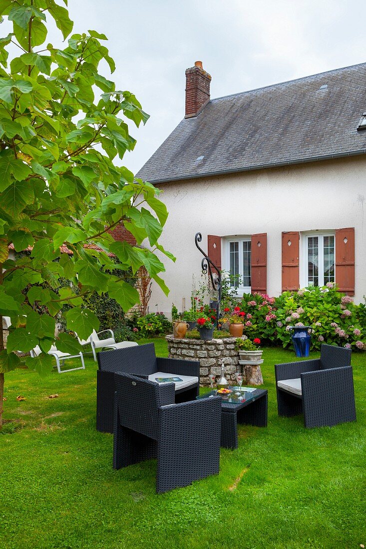 Gartenplatz mit modernen Outdoormöbeln vor renovierter Bauernhausfassade