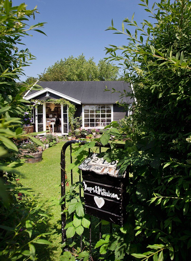 Blick von sommerlichem Garten auf kleines Sommerhaus mit weissen Sprossenfenstern