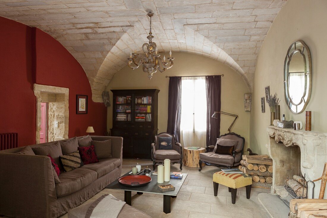 Sofa, simple coffee table and open fireplace in rustic interior with vaulted ceiling