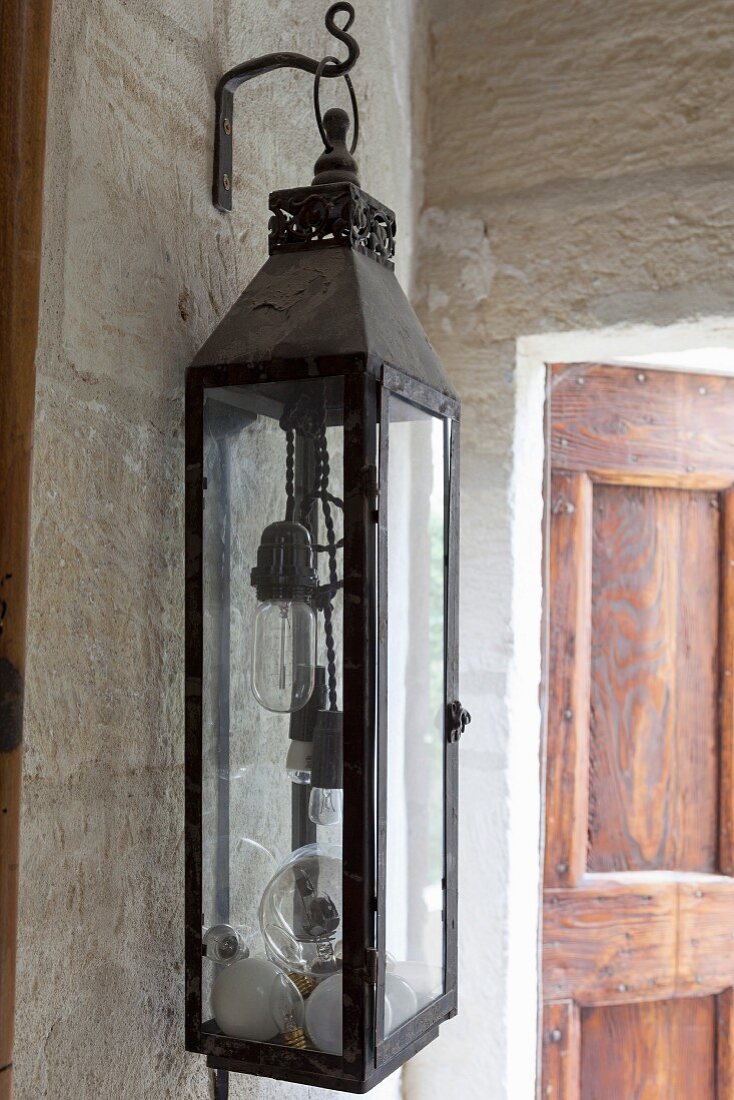 Lantern filled with light bulbs hanging on stone wall