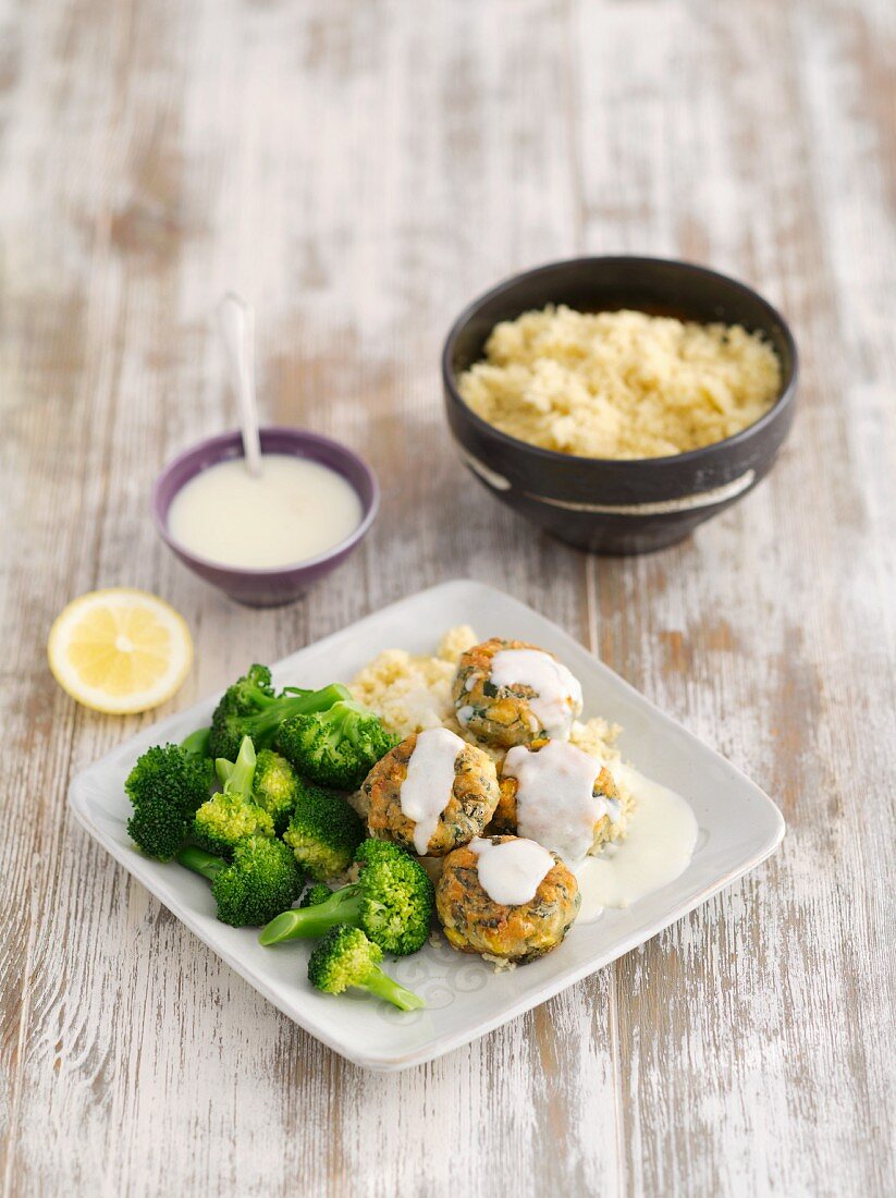 Salmon cakes with sweetcorn and spinach on a creamy lemon sauce served with broccoli and couscous