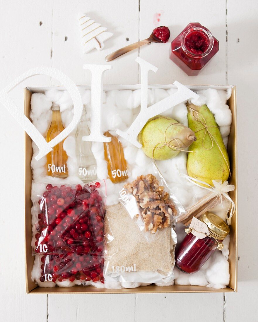 Pear, walnut and cranberry sauce in a jar with ingredients in a gilded crate