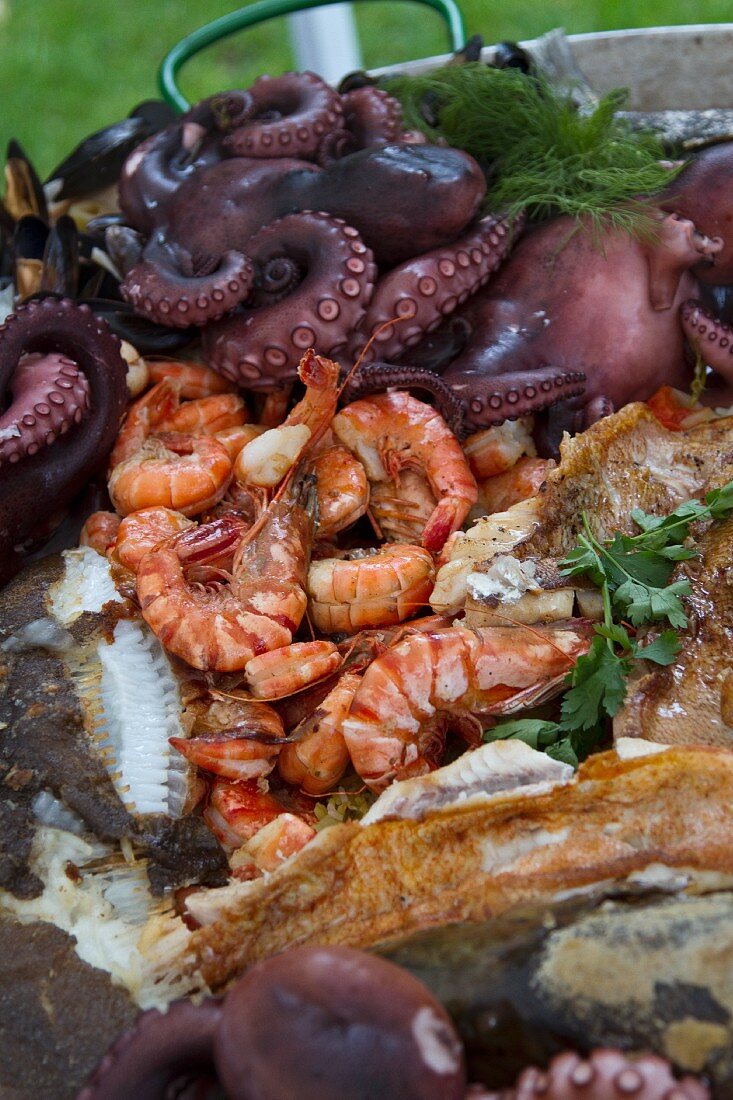 Fried fish, prawns and octopus in a bowl in a garden