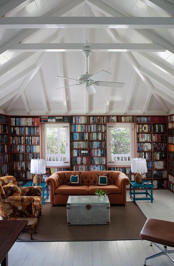 Umlaufende Bücherwände in quadratischem Raum mit Zeltdachkonstruktion; in der Mitte eine Retro Sitzgruppe in Naturtönen