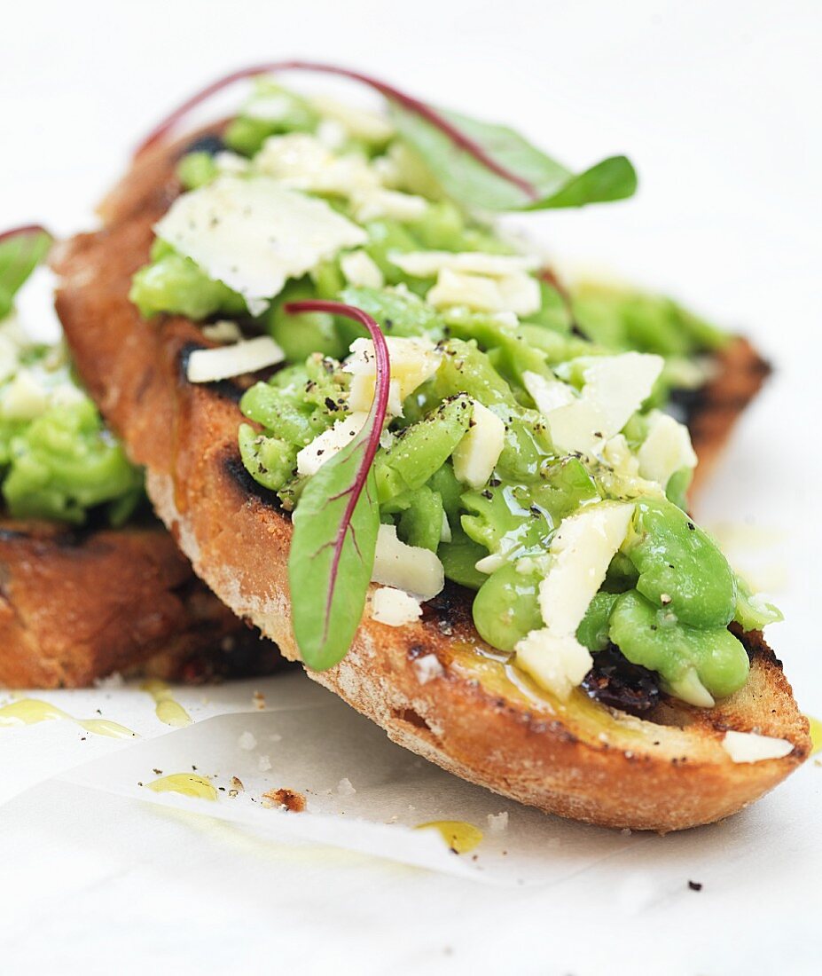 Bruschetta topped with broad beans, olive and cheese (close-up)