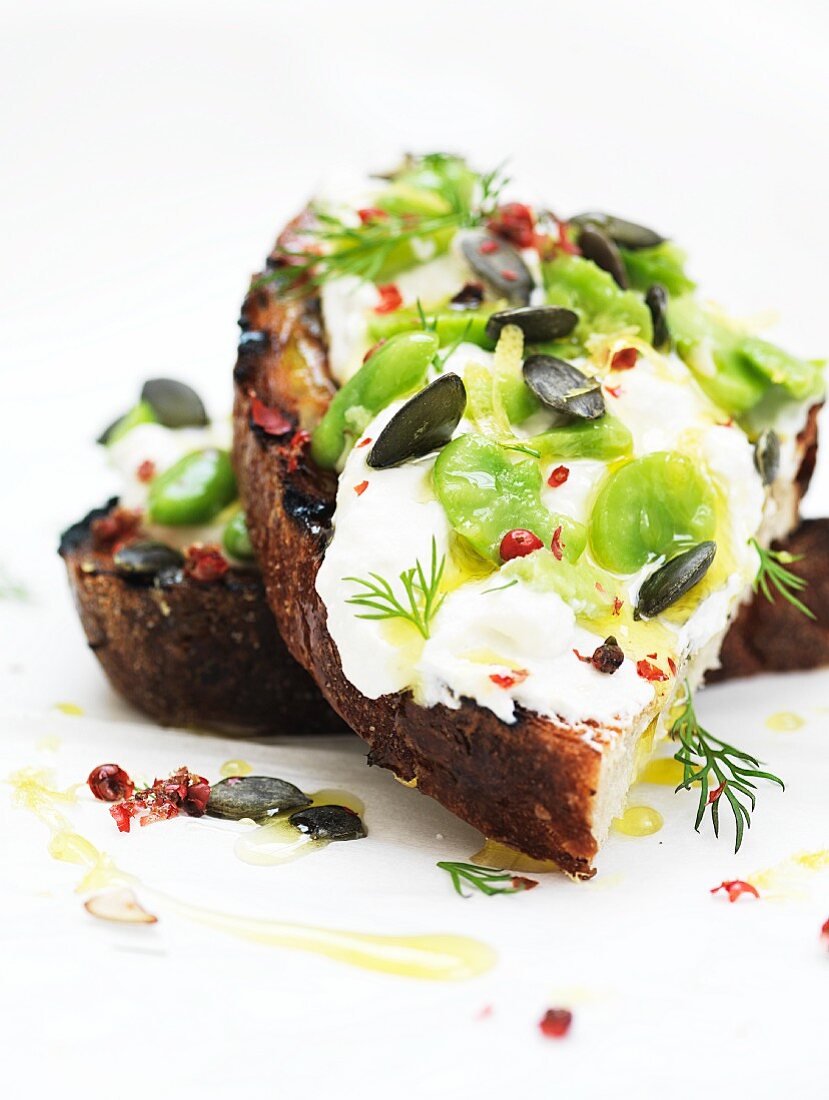 Bruschetta topped with ricotta, broad beans and pumpkin seeds