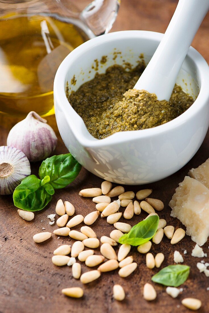 Pesto in mortar surrounded by ingredients