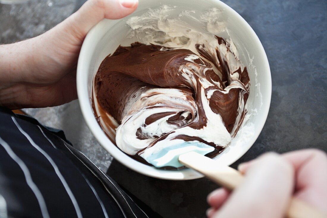 Chocolate and vanilla frosting being stirred in a bowl