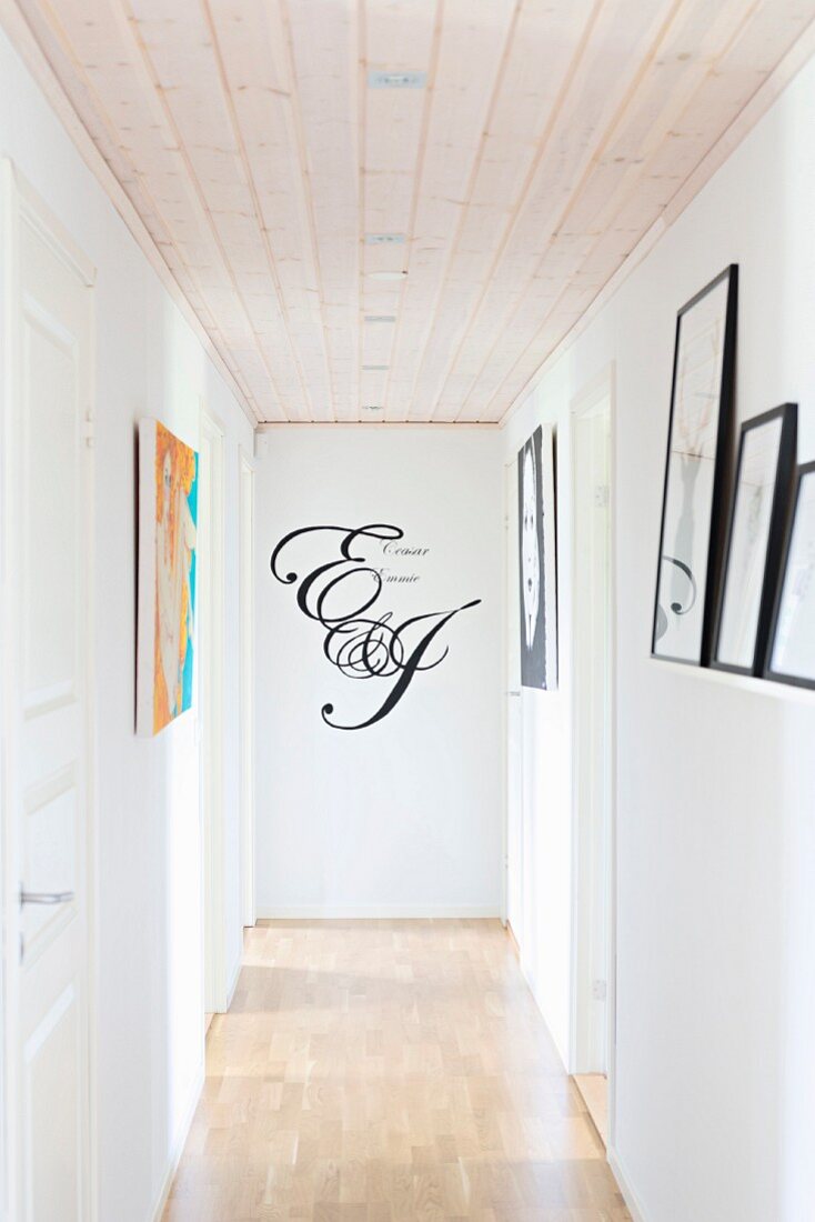 Narrow hallway with wooden floor and ceiling and motto written on end wall