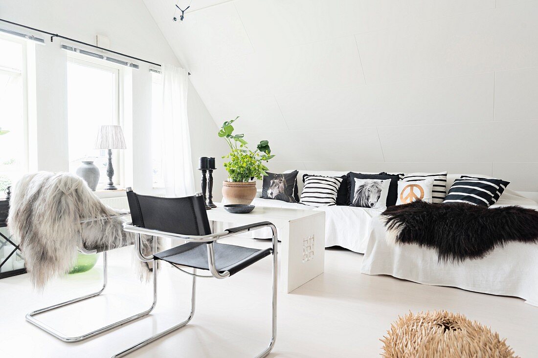 Black, leather, cantilever chair and sofa with scatter cushions in attic lounge