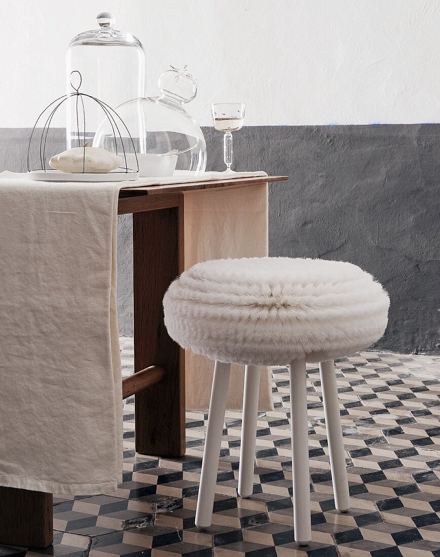 White stool on grey and white floor tiles at table with glass covers and glass of white wine