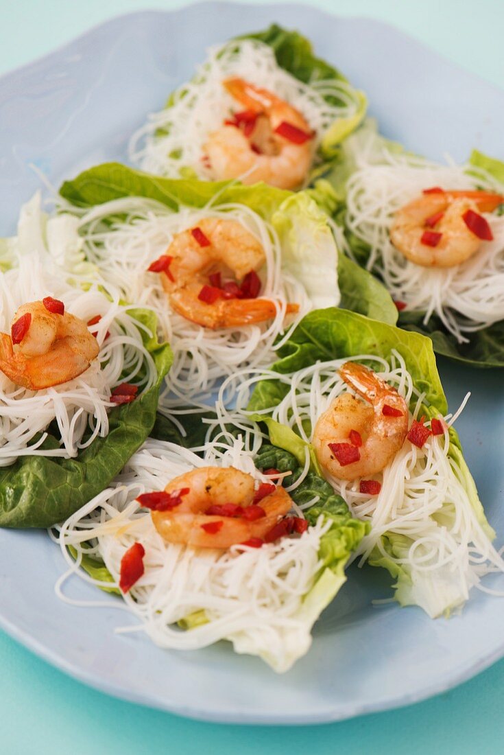 Mini glass noodle nests with spicy prawns on lettuce leaves