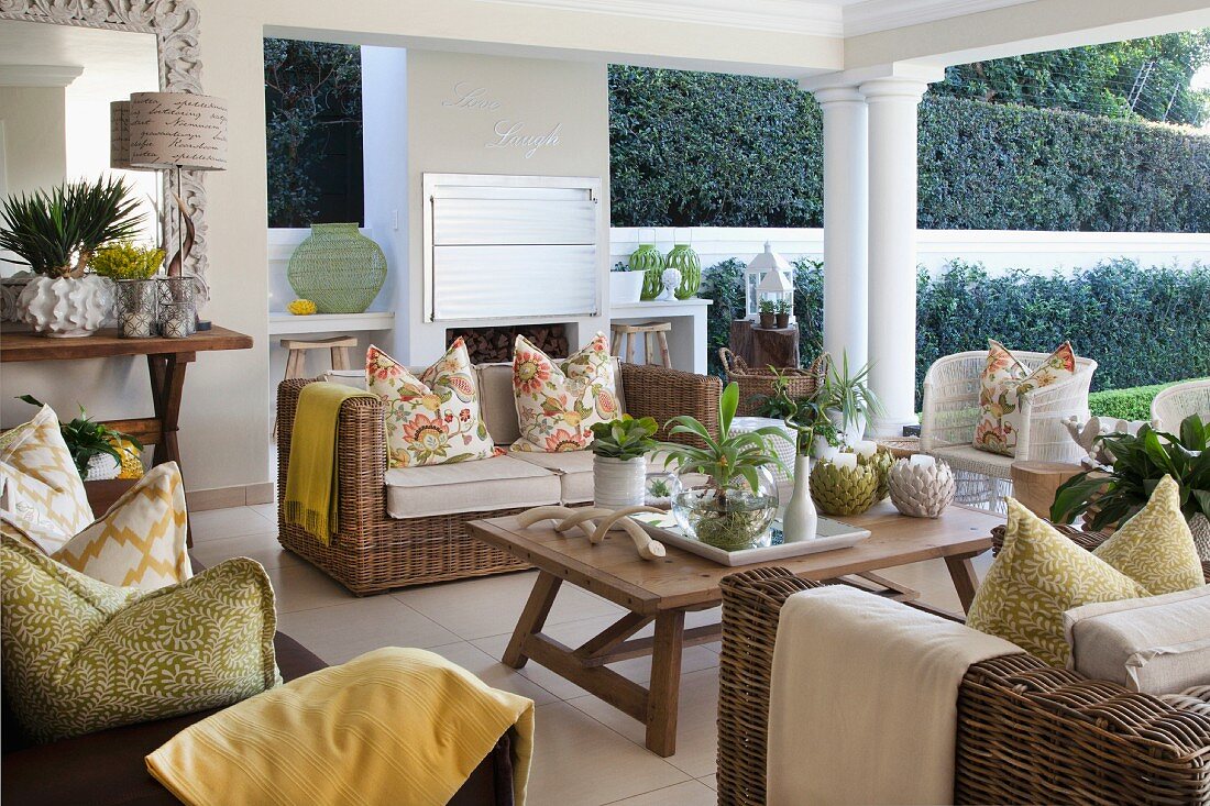 Wicker furniture and yellow and green accents in seating area on roofed patio