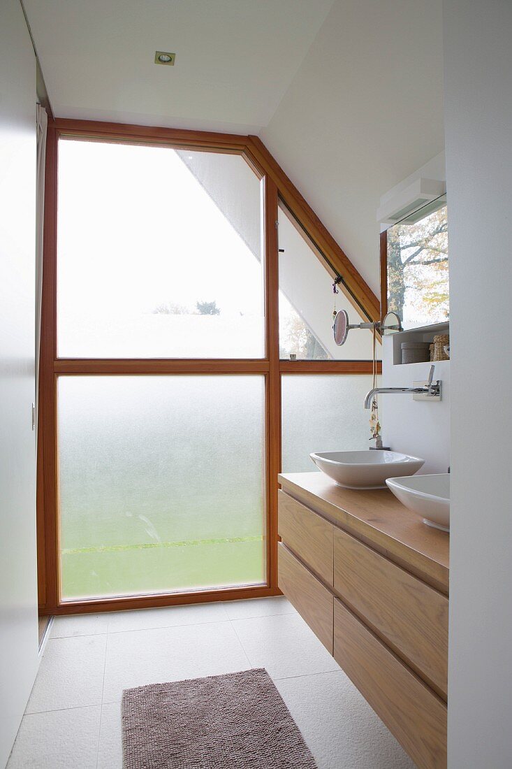 Modern washstand with wooden base unit and opaque glass façade with wooden frame in background