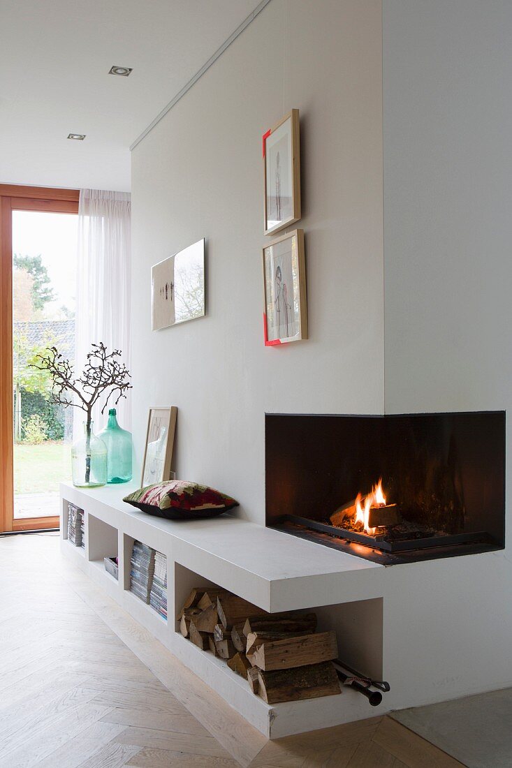 Fire in open fireplace and low sideboard integrated into wall