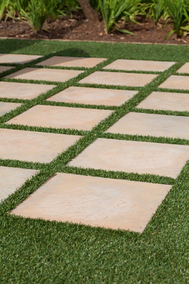 Terrace made from widely spaced stone flags laid in artificial lawn