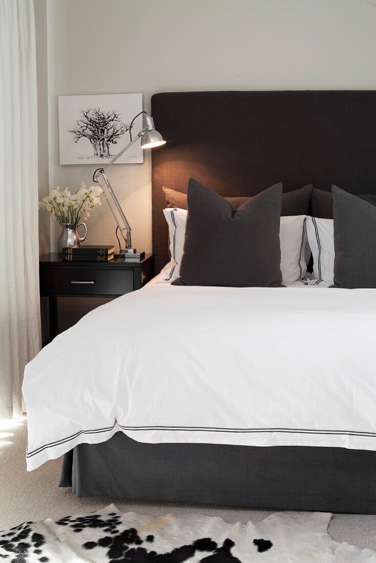 Scatter cushions and white throw on double bed with charcoal-grey headboard