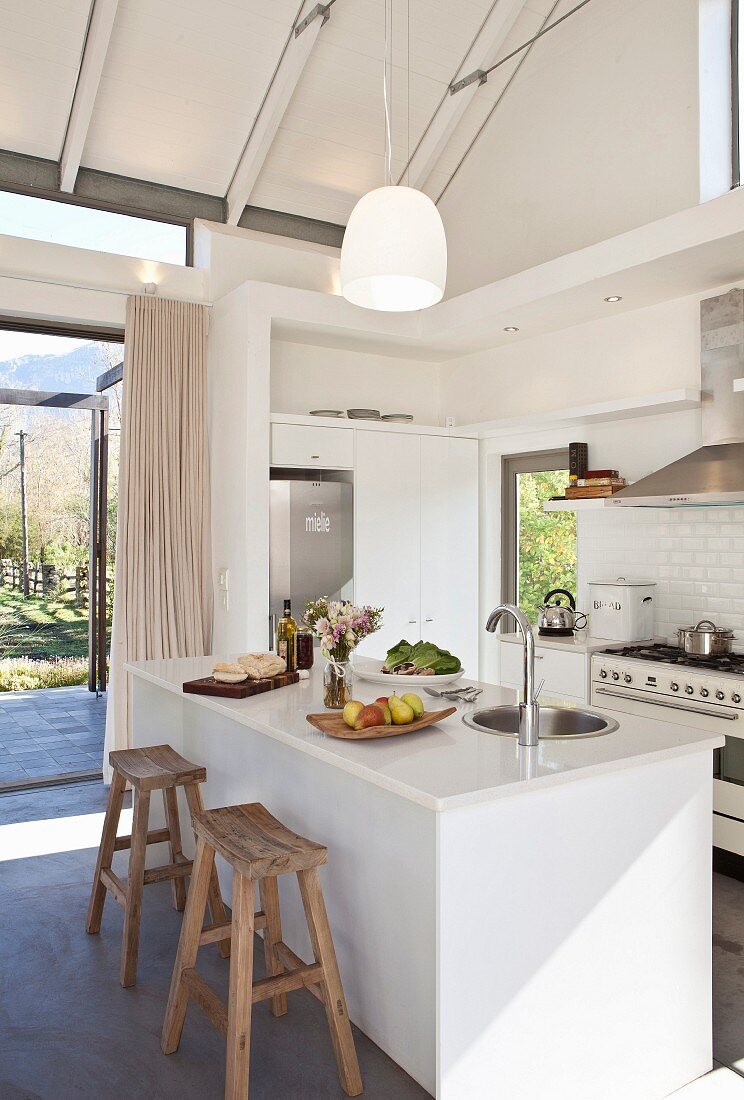 White open-plan kitchen with island counter and exposed beams in open roof area