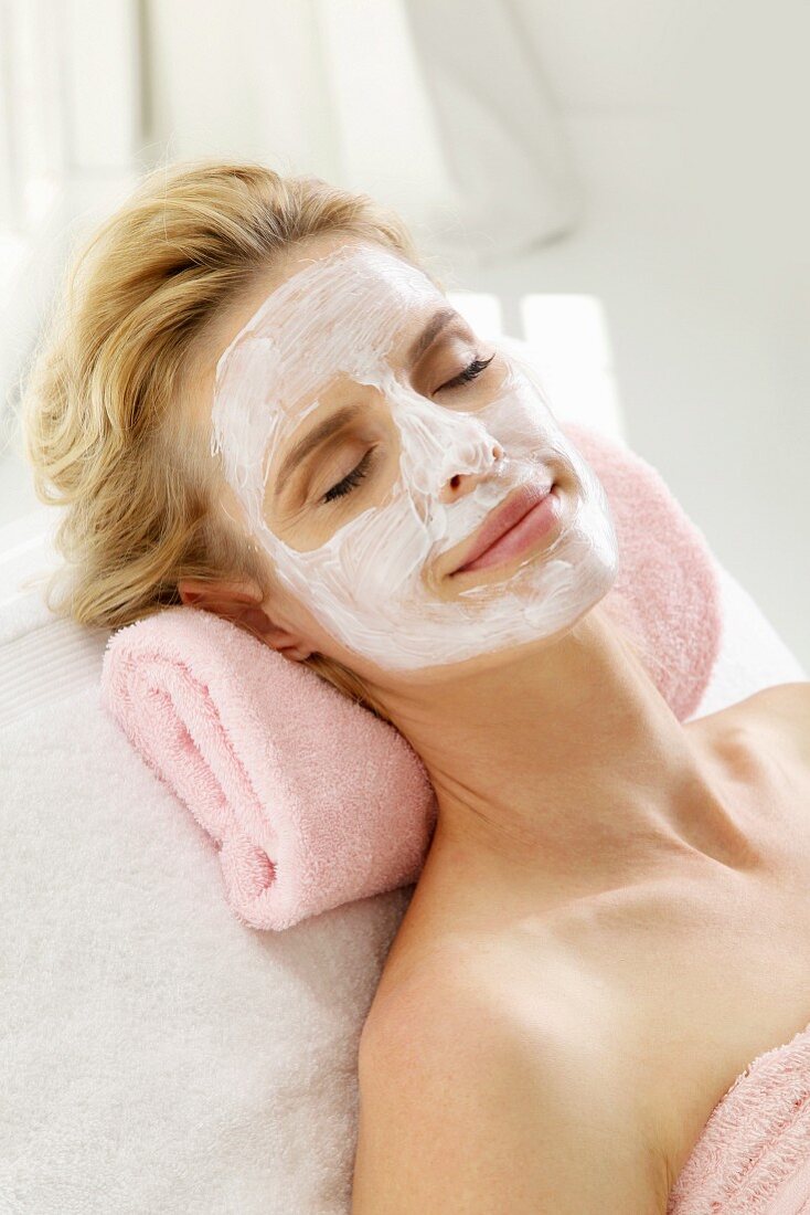 A blonde woman relaxing with a nourishing face mask