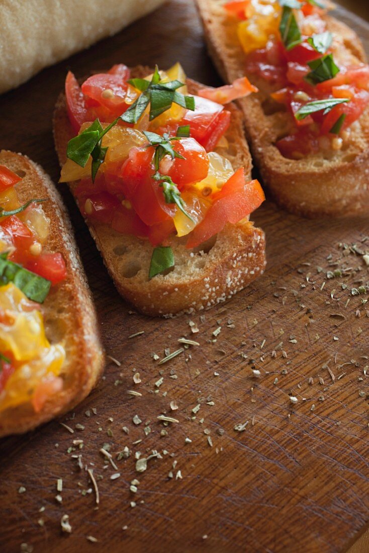 Bruschetta topped with basil and seasonings on a wooden surface