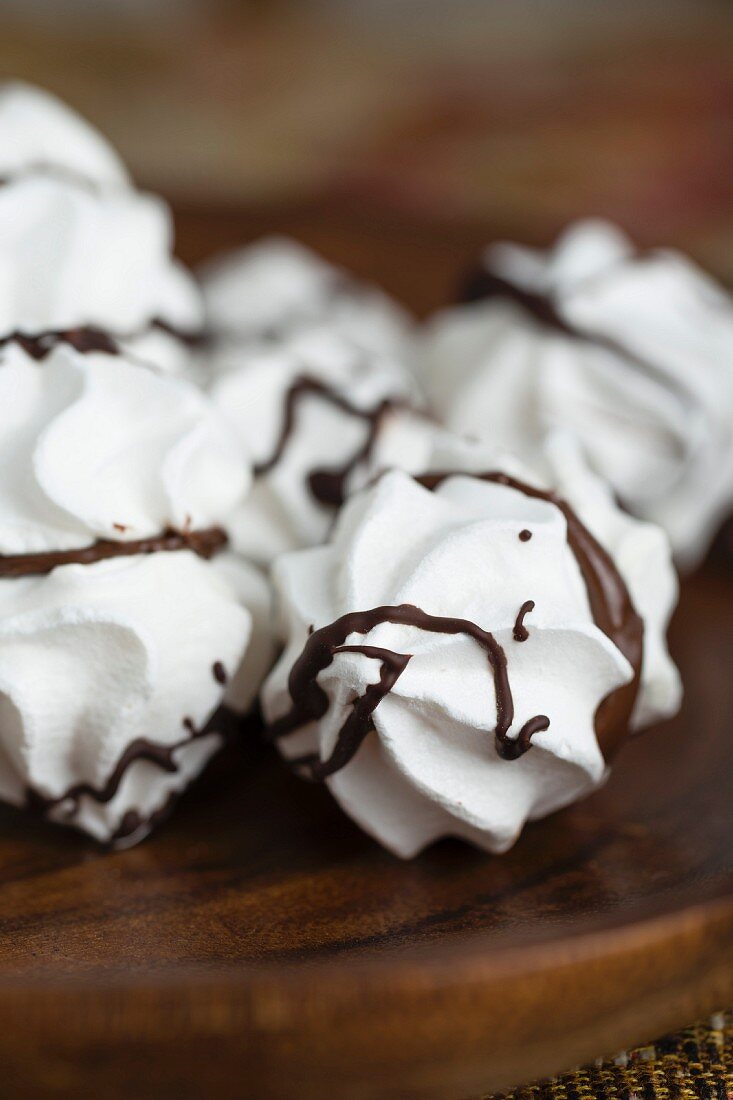 Meringues with chocolate and chocolate cream on a wooden plate