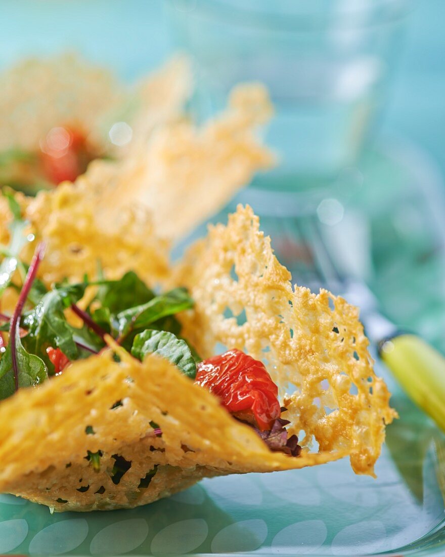 A mixed leaf salad with tomato confit in a Parmesan basket