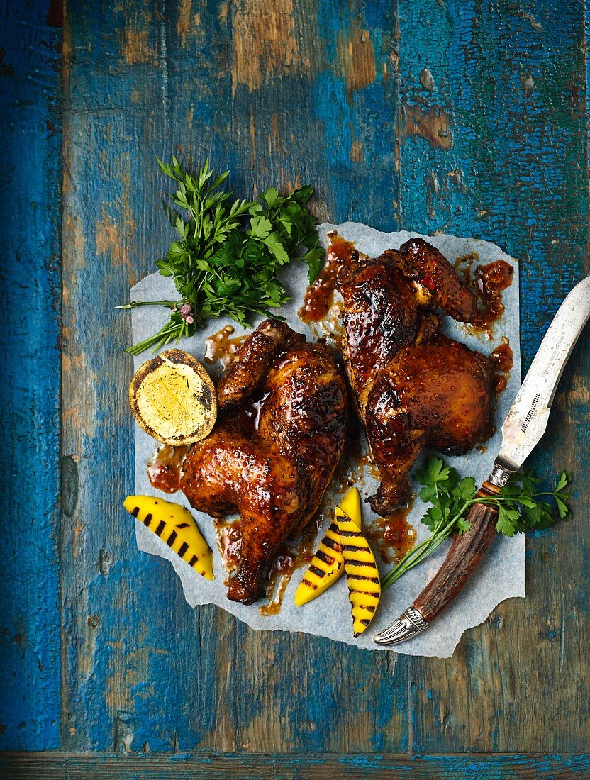 Gegrilltes Hickory-Peri-Peri-Hähnchen mit Mango und Petersilie auf Papier