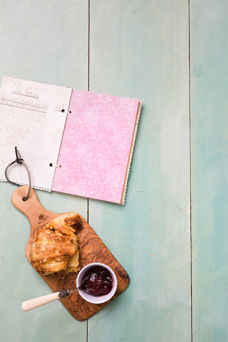 Almond pastries with jam on a wooden board next to a book