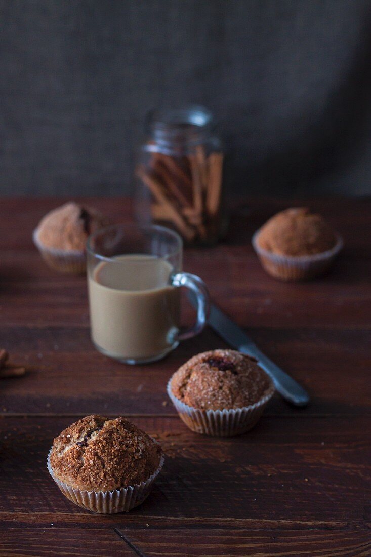 Homemade cinnamon muffins, a cafe latte and cinnamon sticks