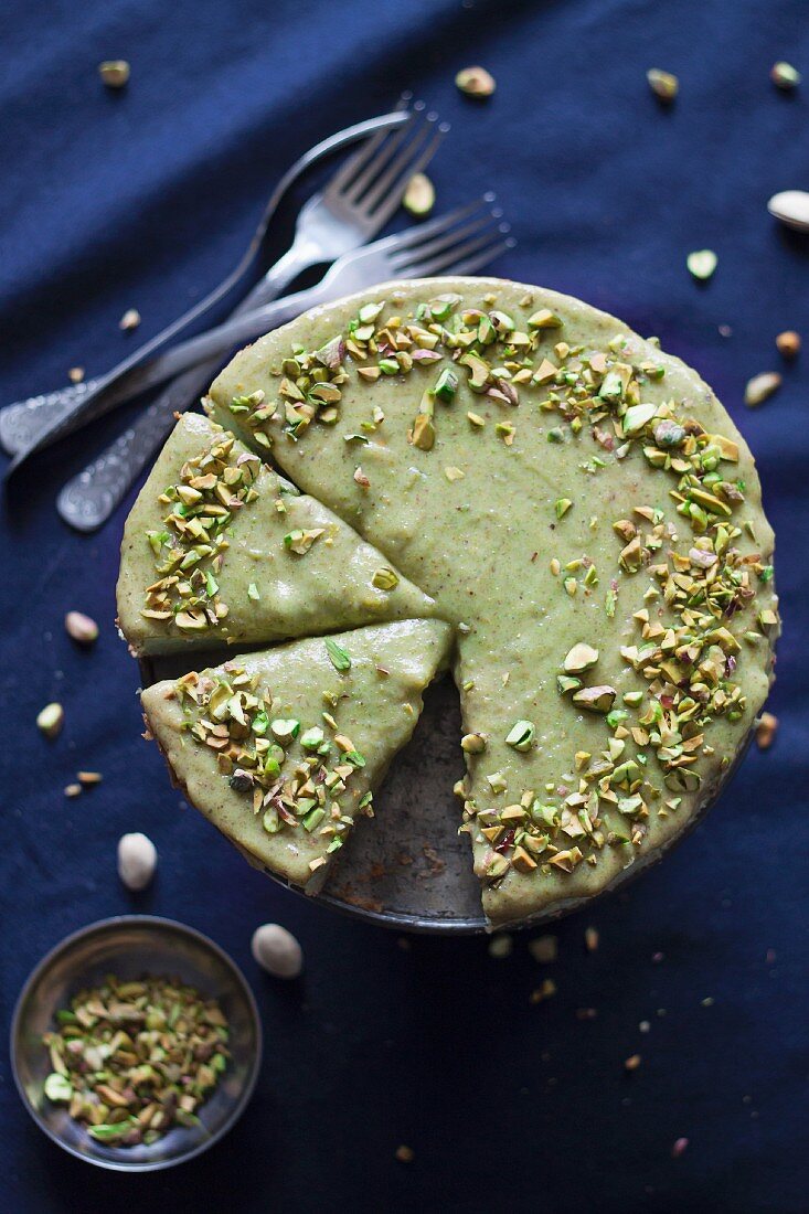 Pistachio cheesecake with a pistachio glaze and chopped pistachios, sliced (seen from above)