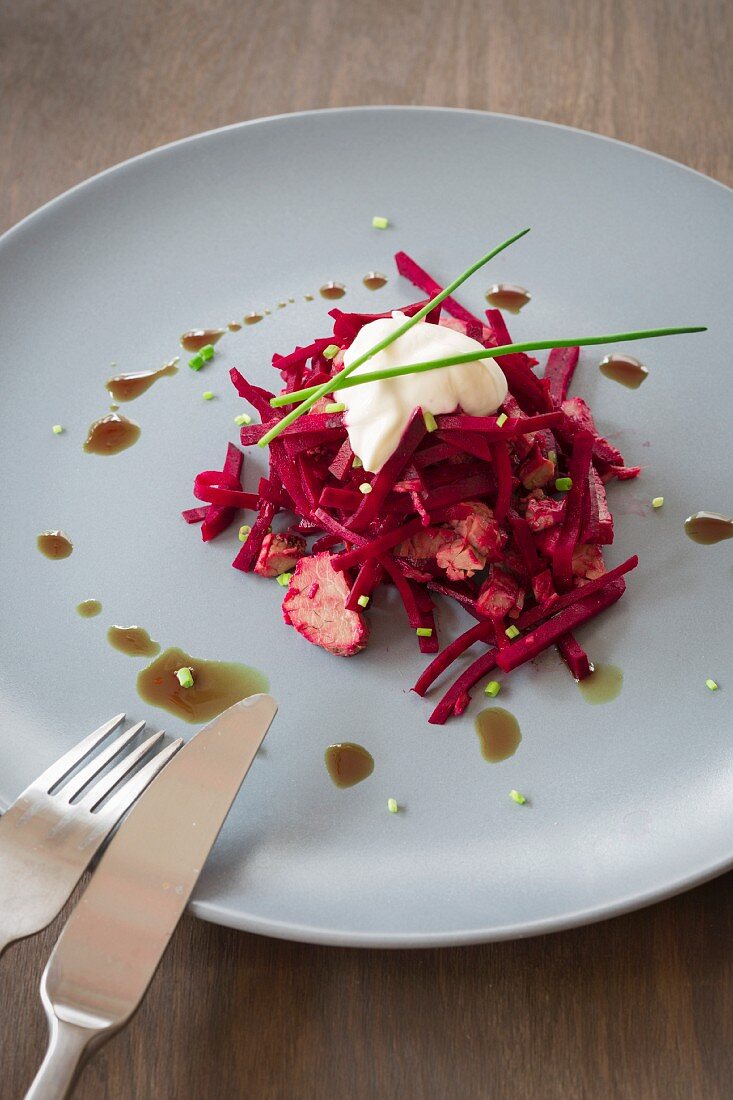 Rote-Bete-Salat mit Tafelspitz auf Teller mit Kürbiskernöl, Schnittlauch und Creme fraiche