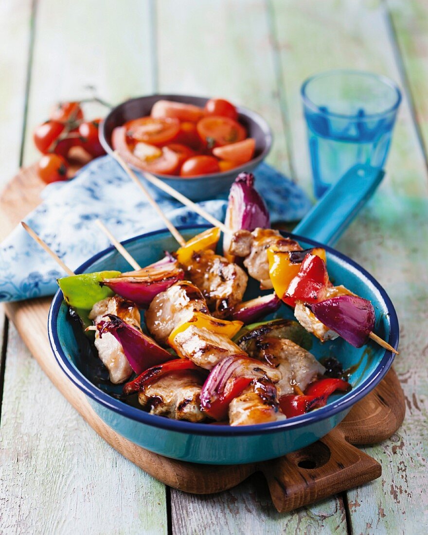 Pork skewers with peppers, onions and tomato salad