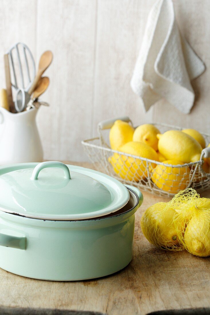 A cooking pot and fresh lemons on a wooden table