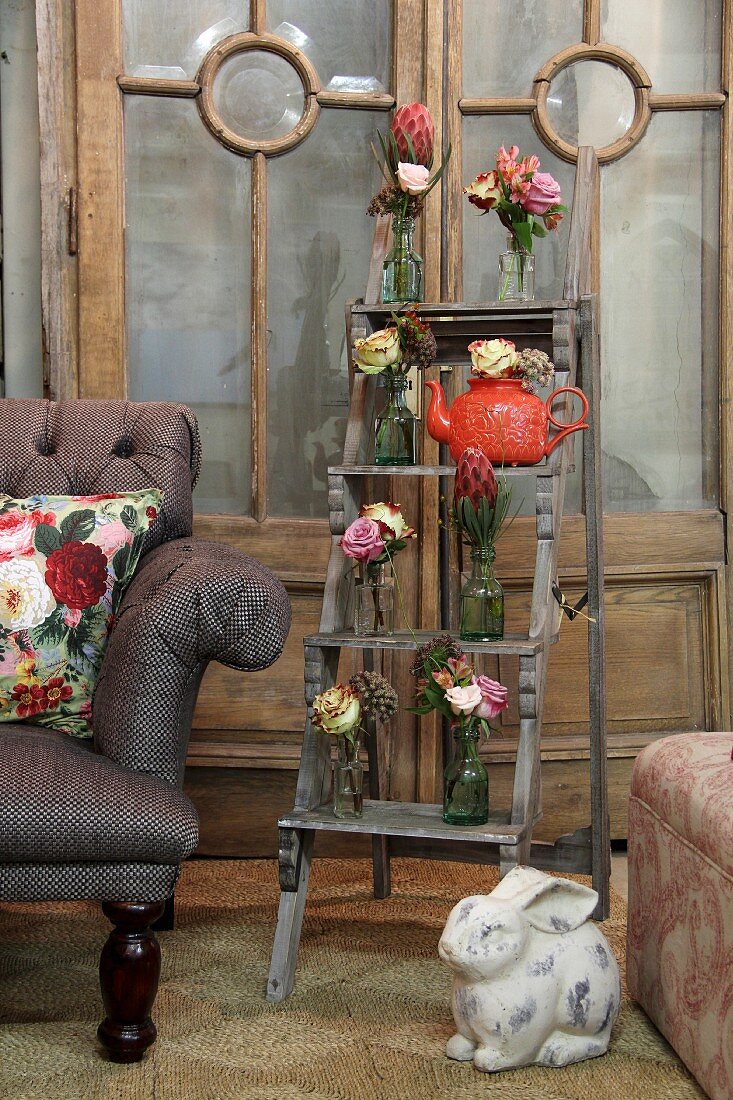 Posies in recycled glass bottles arranged on rustic wooden ladder in vintage ambiance