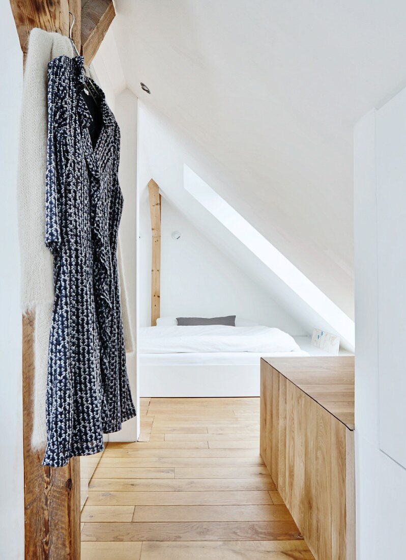 Dressing gown on coat hanger and cubby bed under sloping ceiling in converted modern attic room