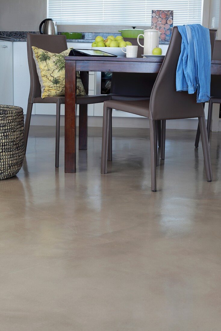 Dark wooden dining table and grey plastic chairs on polished concrete floor